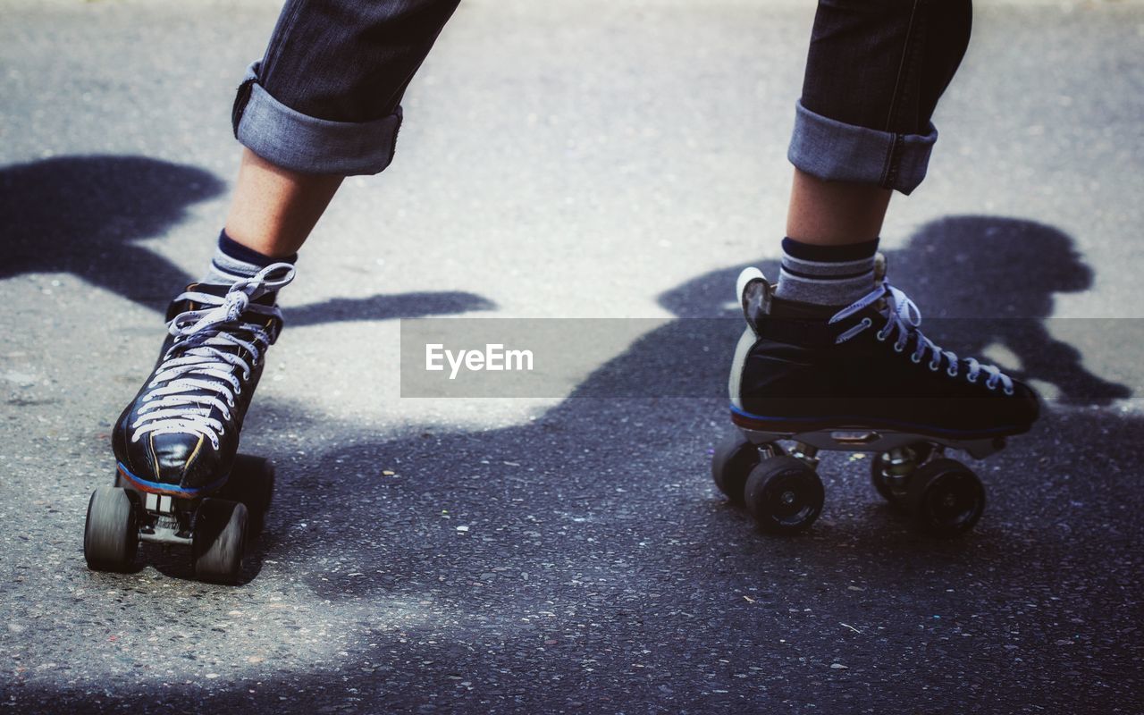 Low section of person roller skating on road