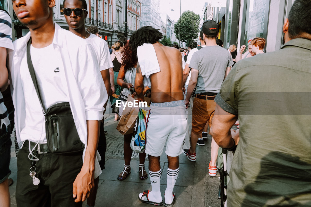 REAR VIEW OF PEOPLE STANDING IN FRONT OF CITY