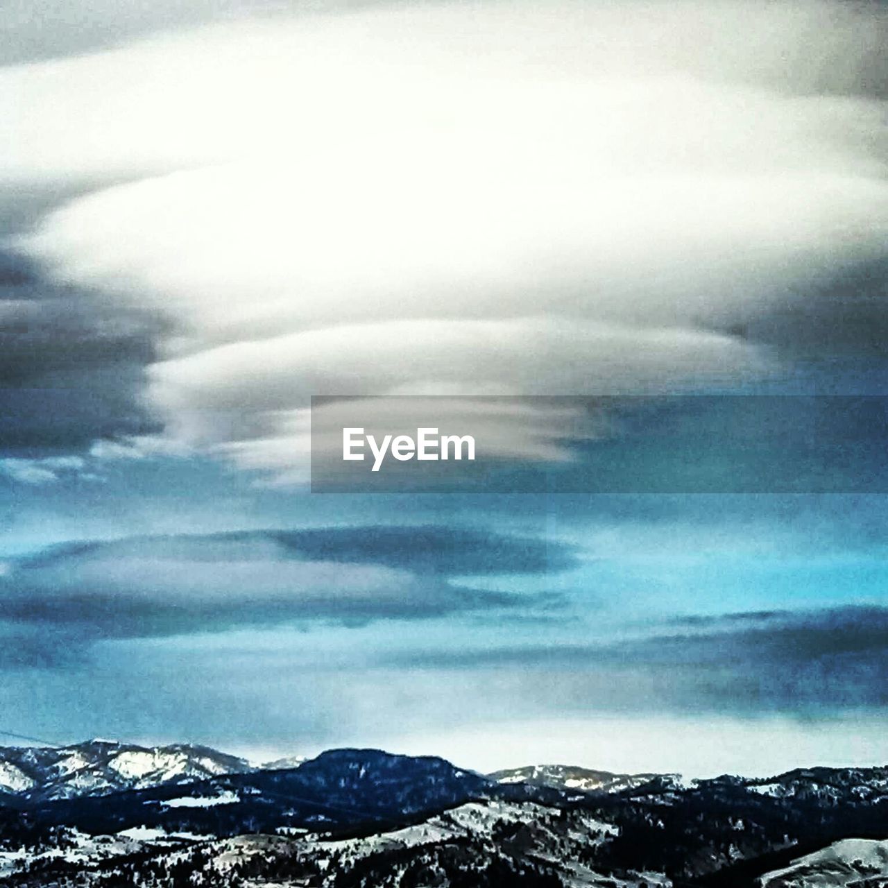 SNOW COVERED MOUNTAINS AGAINST CLOUDY SKY