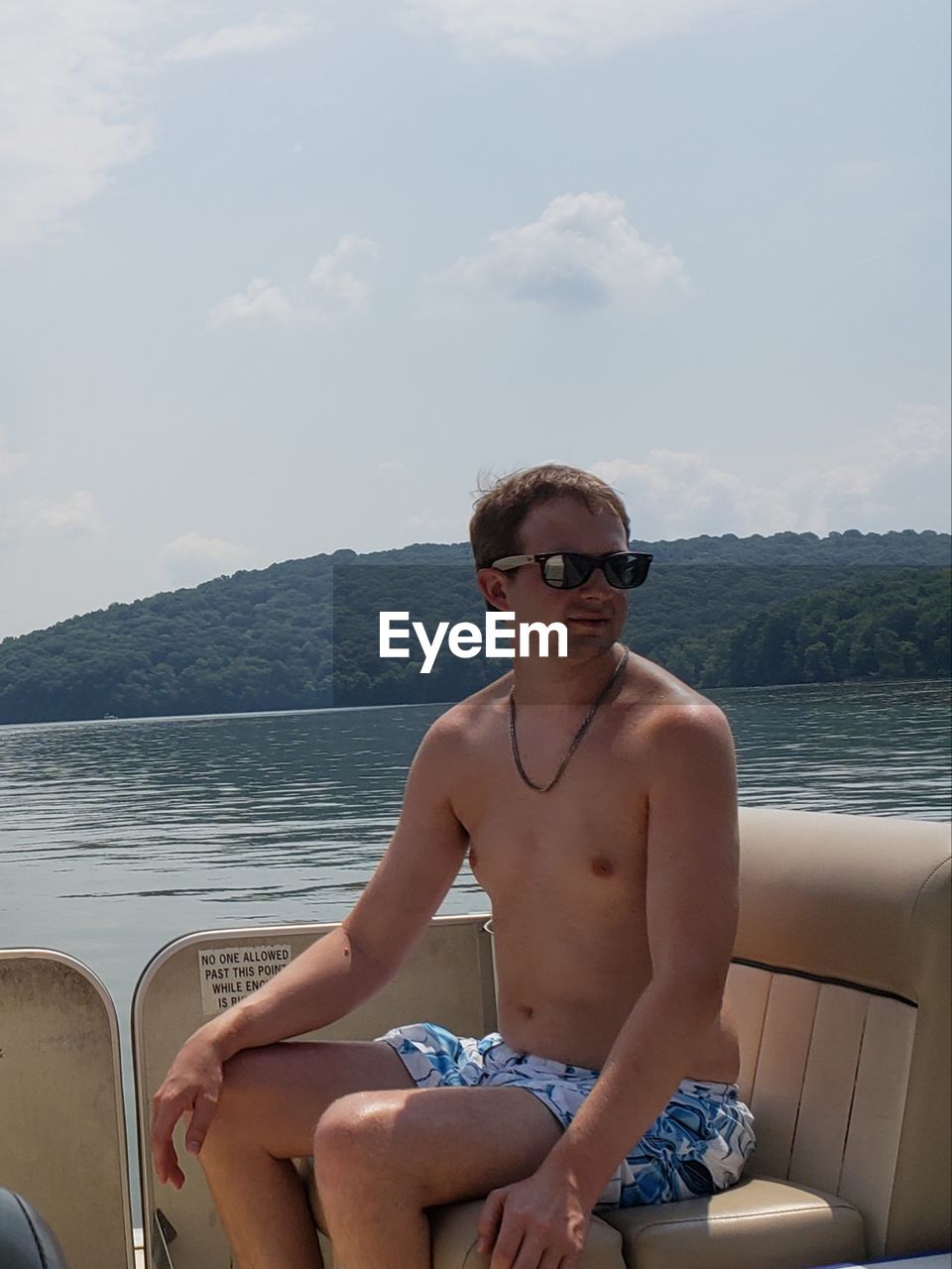 Shirtless man sitting on boat over sea