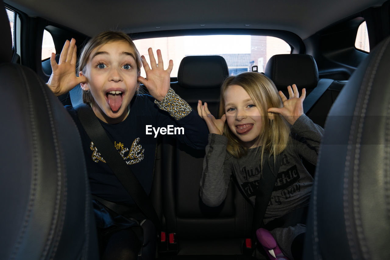 Portrait of children sitting in car making funny faces