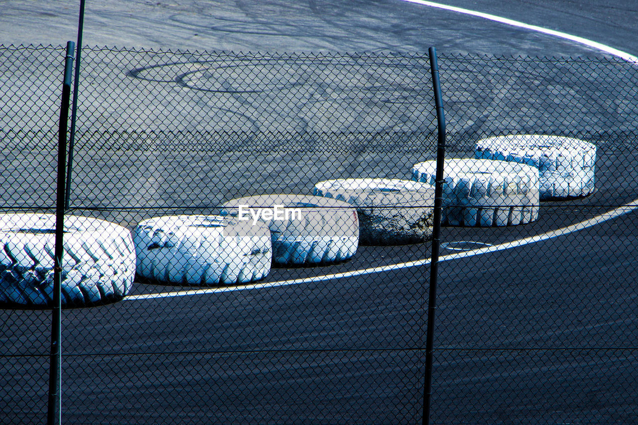 High angle view of tires on sports track seen through fence