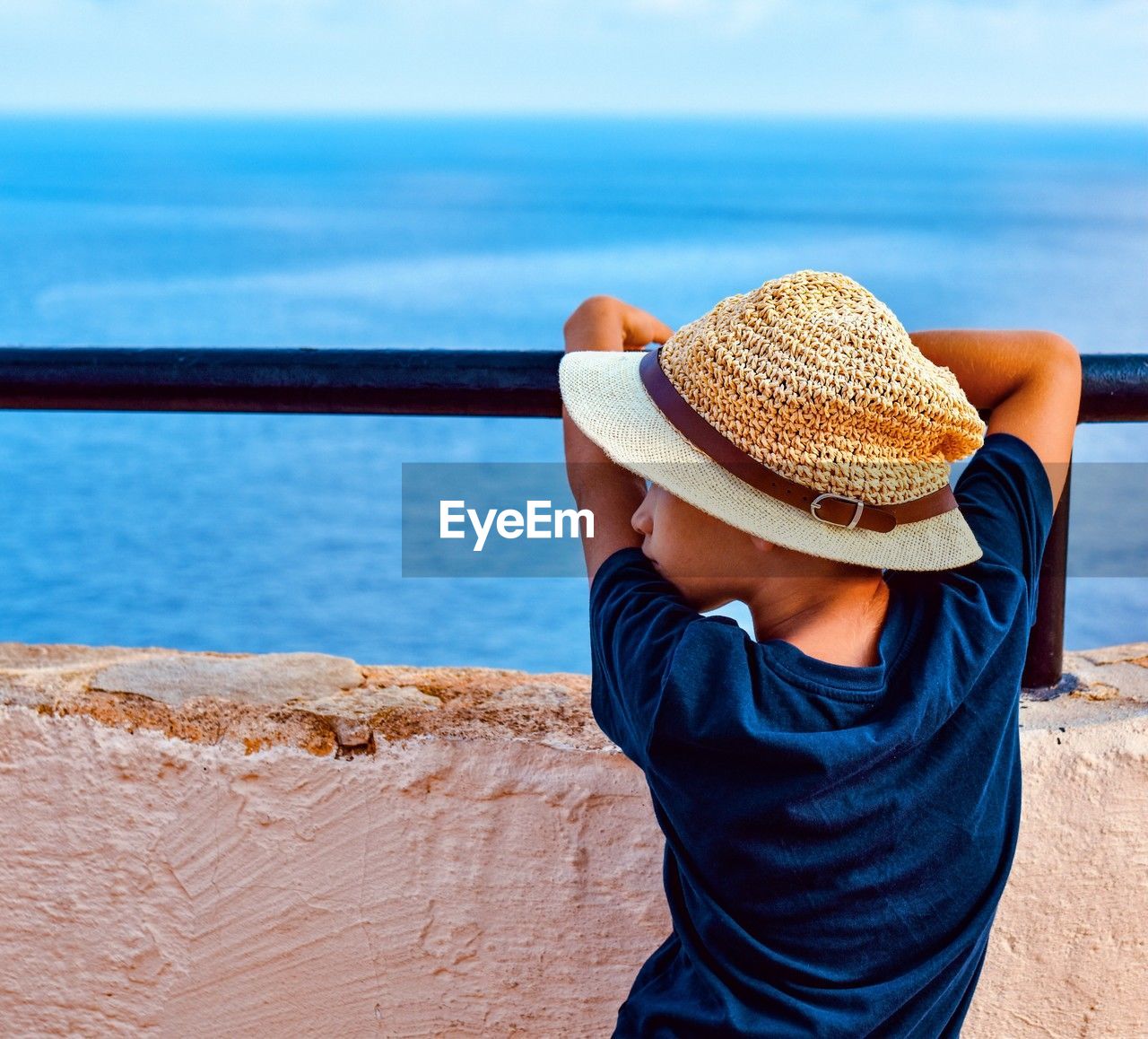 rear view of woman wearing hat standing by railing against sky