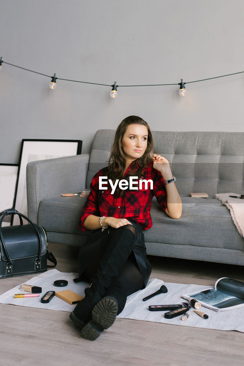 Young beautiful european makeup artist records a review of a cosmetic product, sitting among makeup