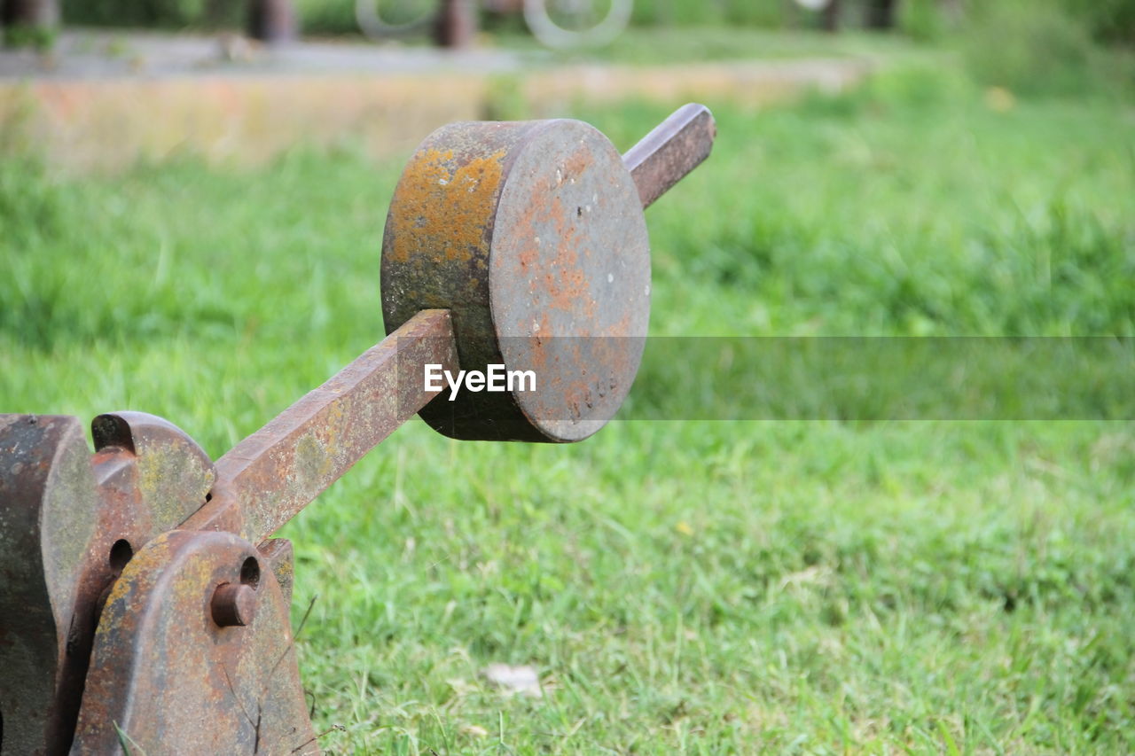 CLOSE-UP OF OLD RUSTY METAL CHAIN ON FIELD