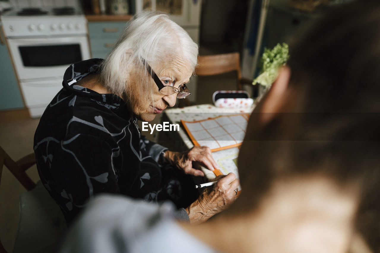 Senior woman talking with female healthcare worker in kitchen at home