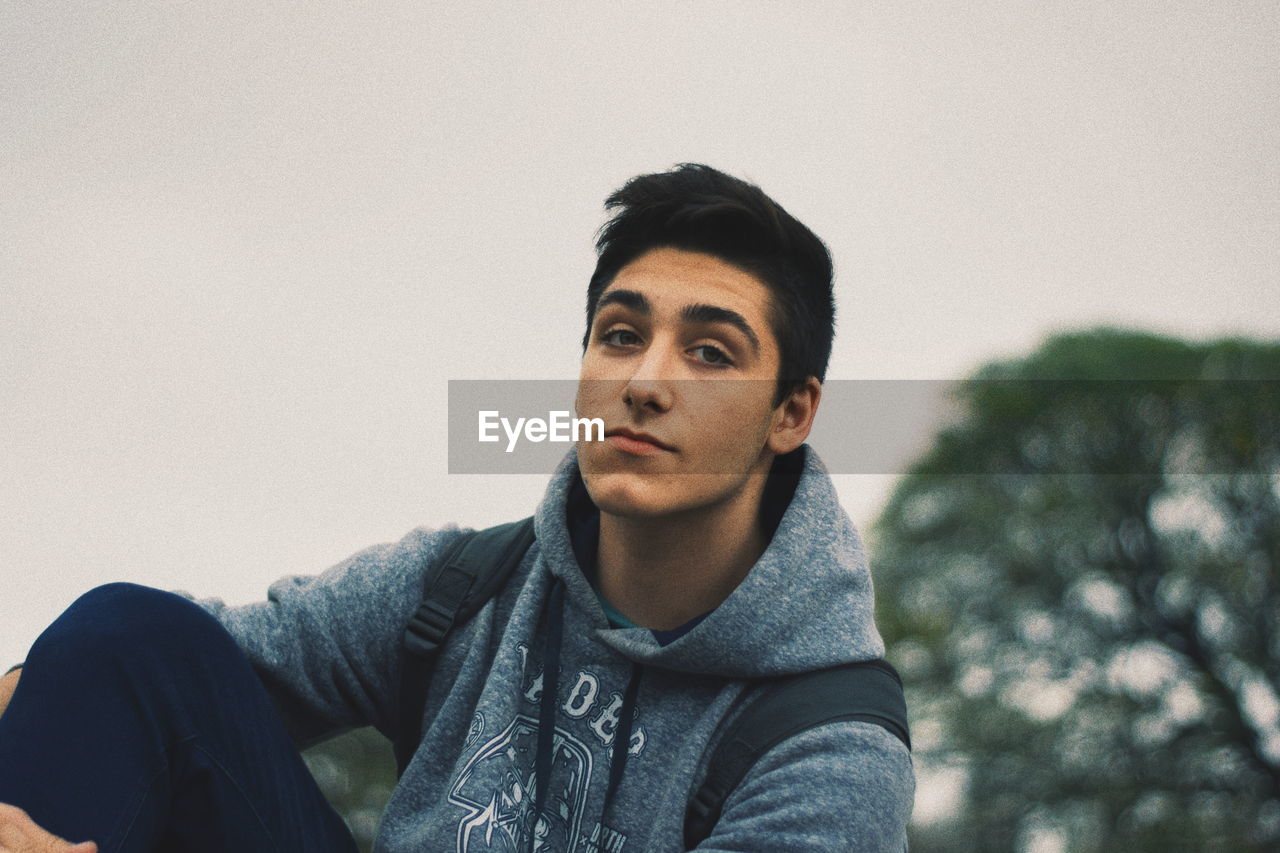 PORTRAIT OF YOUNG MAN LOOKING AWAY AGAINST WALL