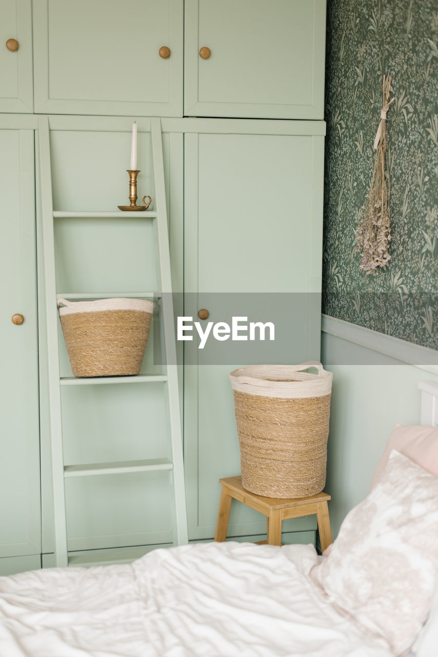 The interior of the bedroom is in the scandinavian style. mint cupboard by the bed and laundry 