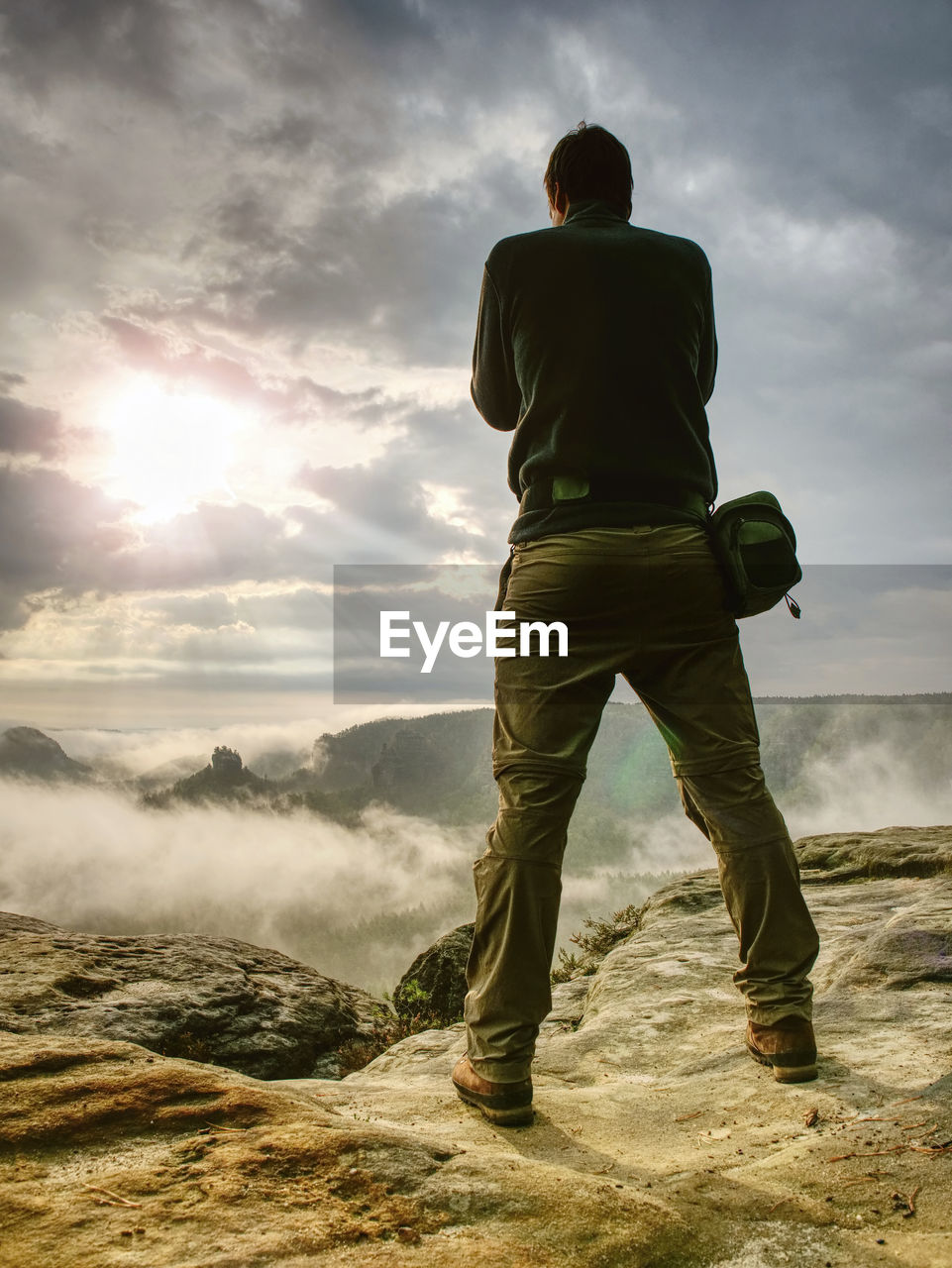 Photographer on cliff with camera viewfinder in his face. nature photographer takes photos on peak