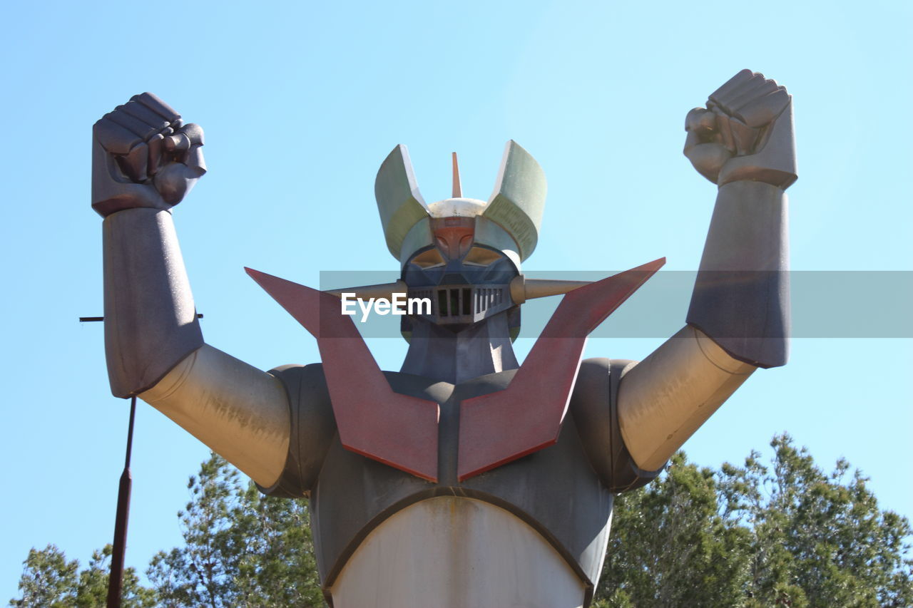 LOW ANGLE VIEW OF MAN HOLDING SCULPTURE