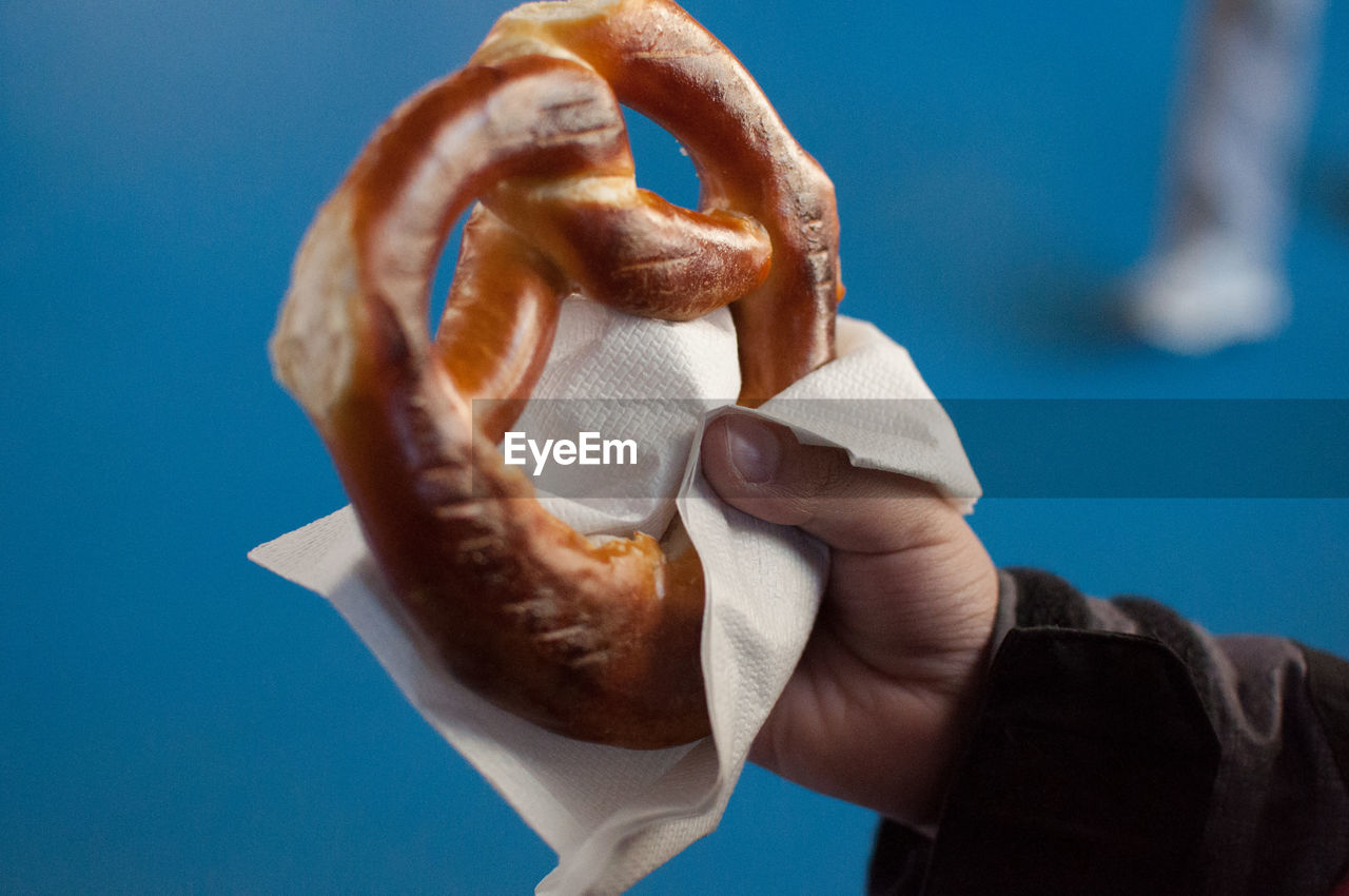 Cropped hand of person holding food against blue background