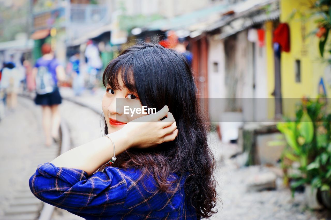 Side view portrait of smiling young woman in town