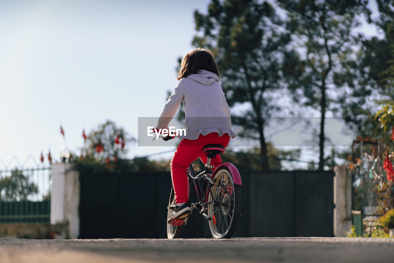 rear view of woman riding bicycle on footpath