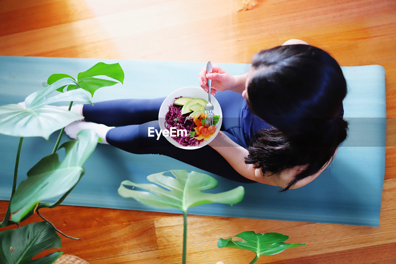 HIGH ANGLE VIEW OF WOMAN SITTING BY PLANT