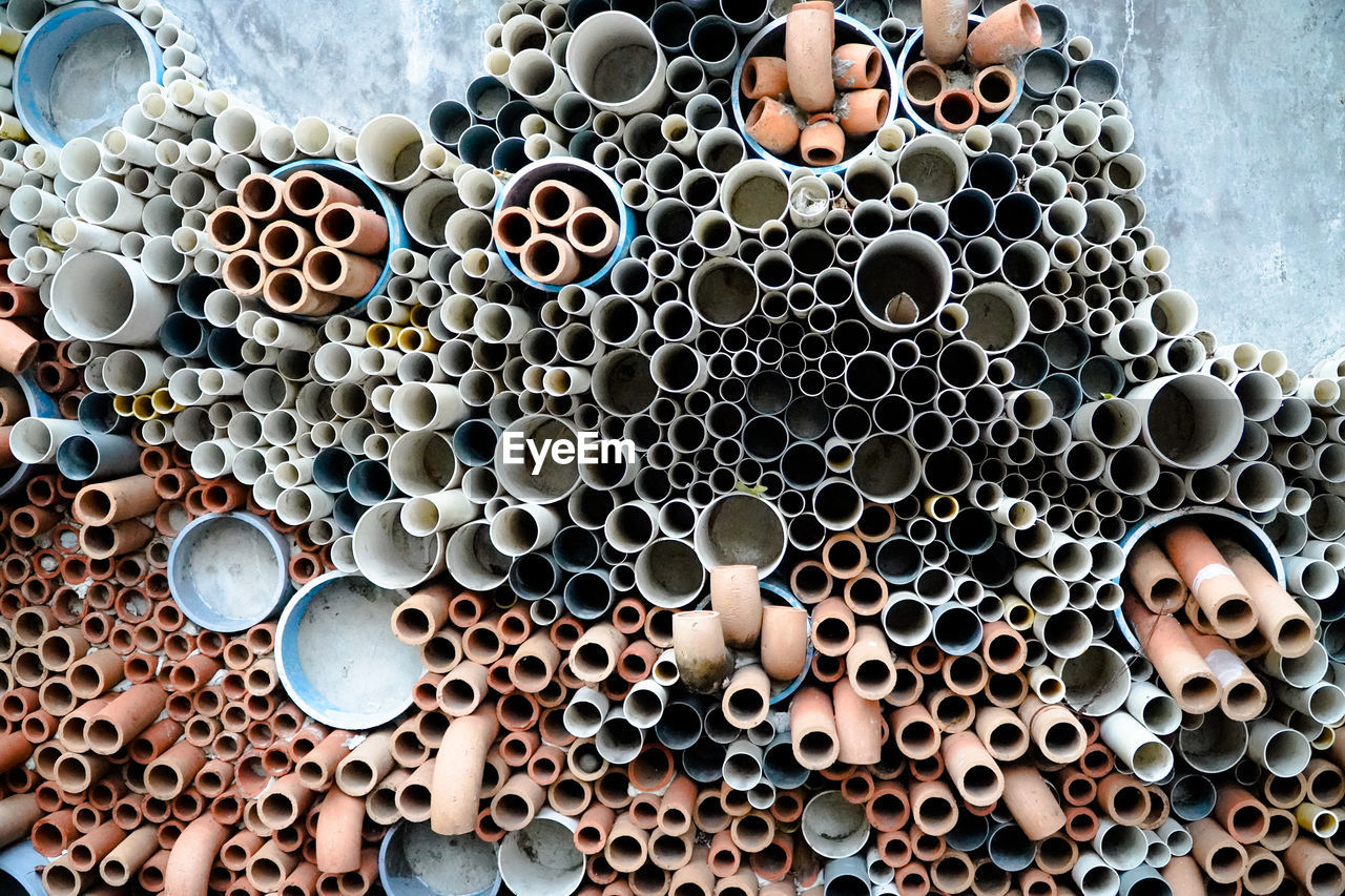 HIGH ANGLE VIEW OF STACK OF PIPES ON WALL