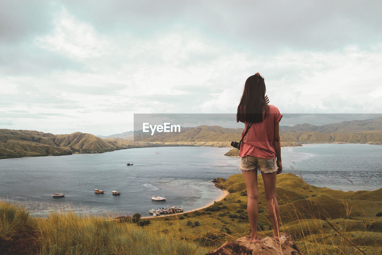 REAR VIEW OF WOMAN LOOKING AT VIEW OF MOUNTAIN AGAINST SKY