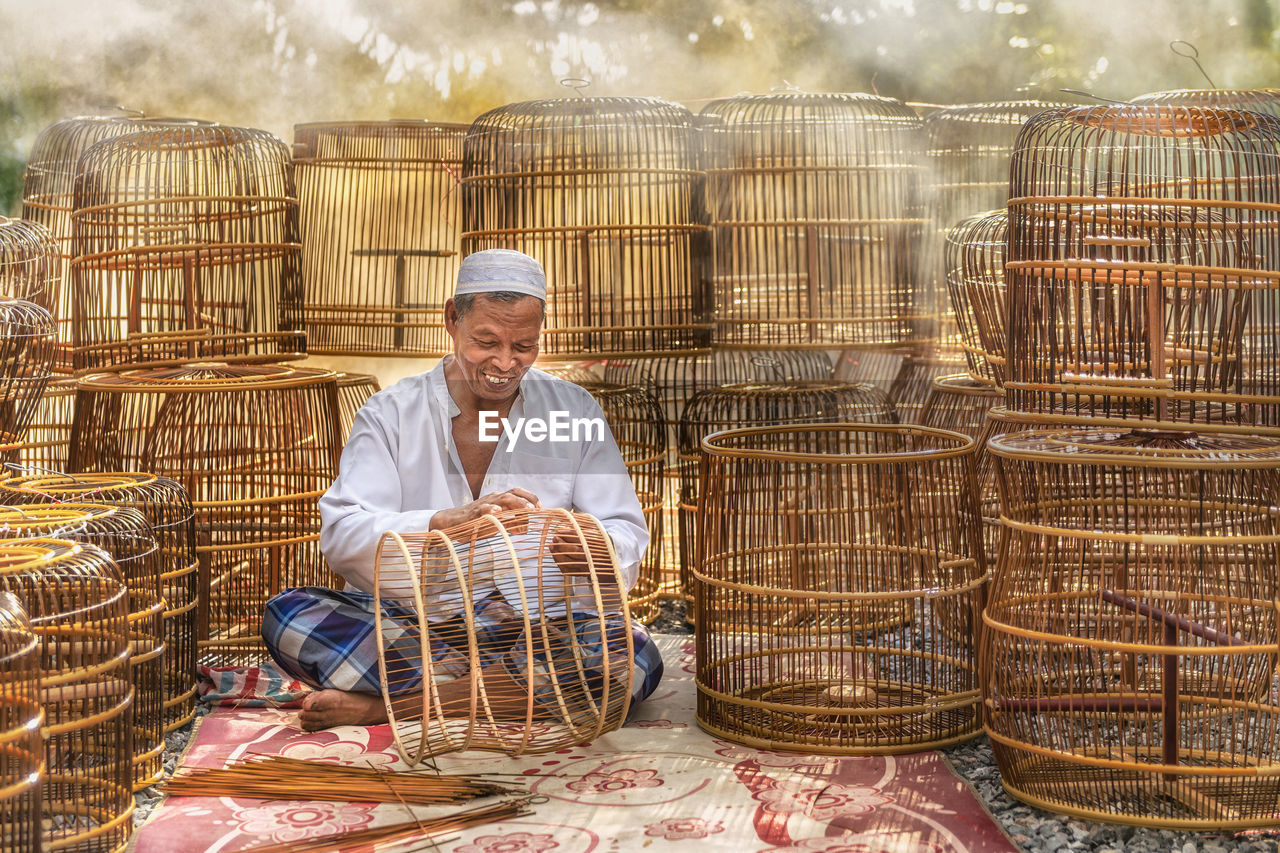 Smiling senior man making wicker baskets