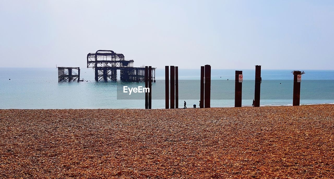 Wooden posts on beach against clear sky