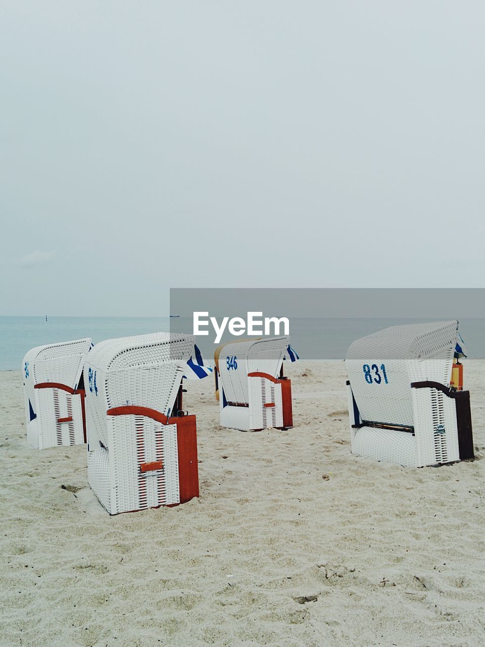 Hooded beach chairs on sand against clear sky