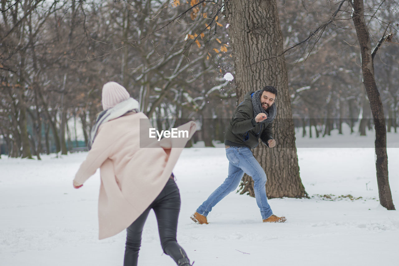 Happy couple playing on snow covered land during winter