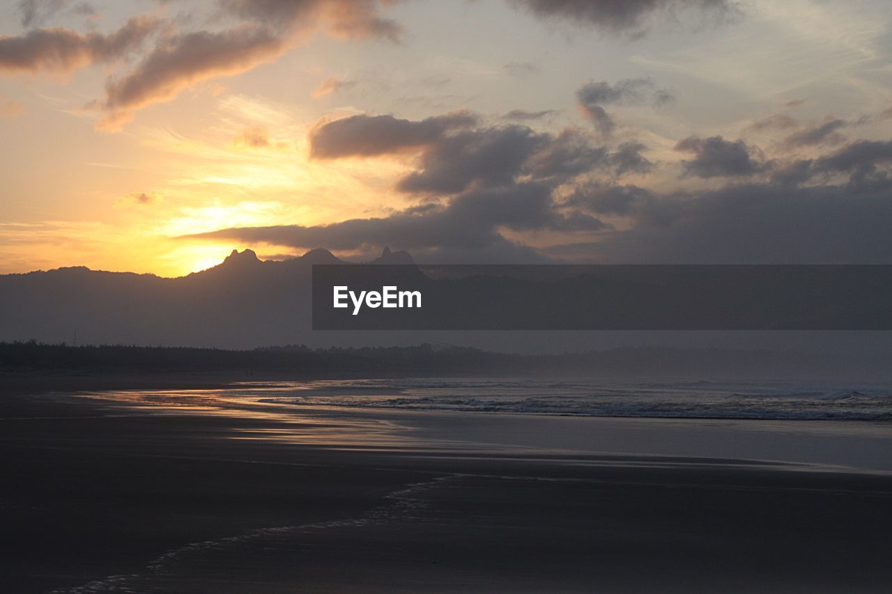 Scenic view of sea against cloudy sky during sunset