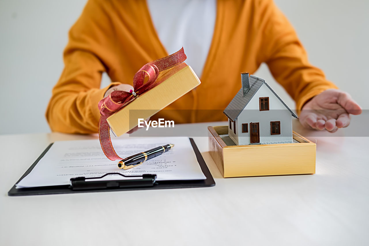 Midsection of businesswoman holding paper while sitting on table