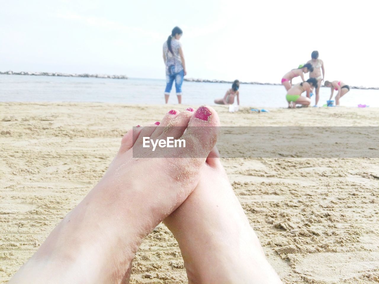 Low section of woman on beach against sky