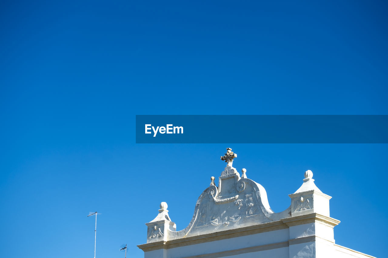 Low angle view of cross on white church against clear blue sky