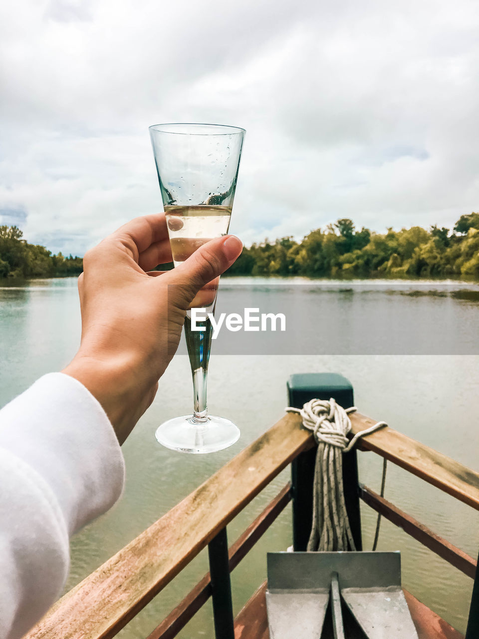 Glass of champagne in hand on the bow of a ship