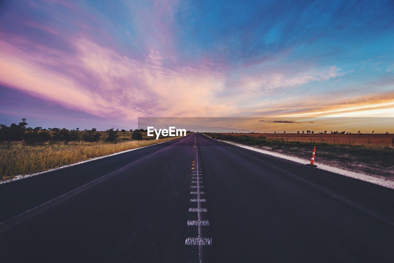 Empty road on field against sky during sunset