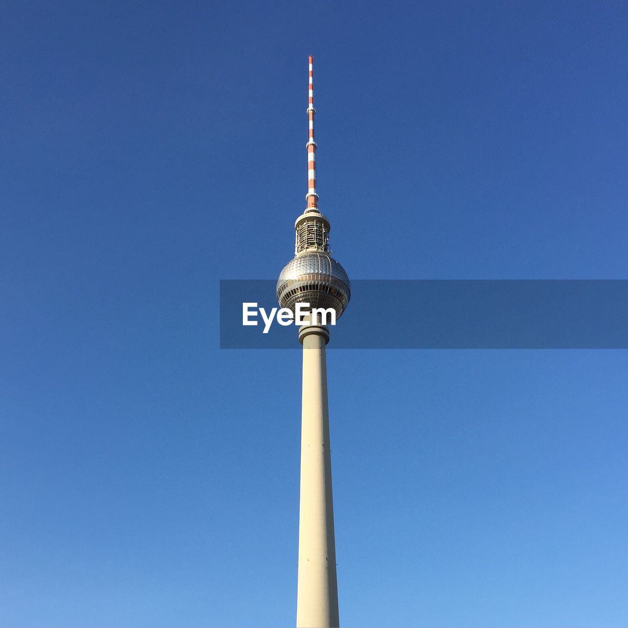 Low angle view of communications tower against clear blue sky