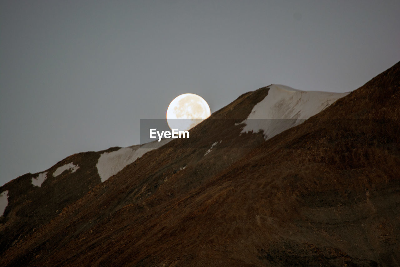 Low angle view of sun shining on mountain against sky