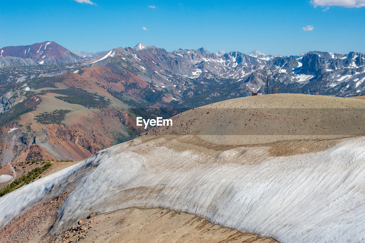 Snow melting at the top of mammoth mountain ca, revealing the colorful mountains in the background