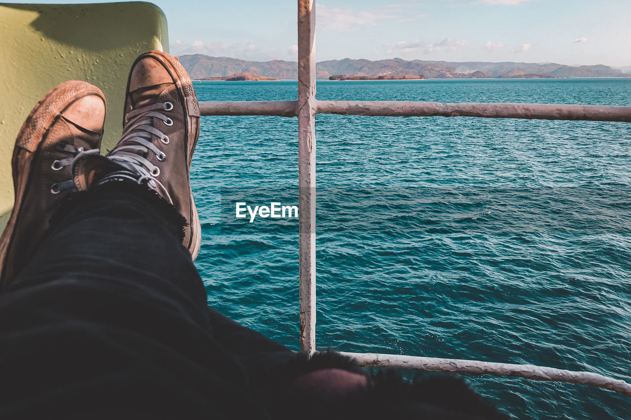 Low section of man relaxing by sea