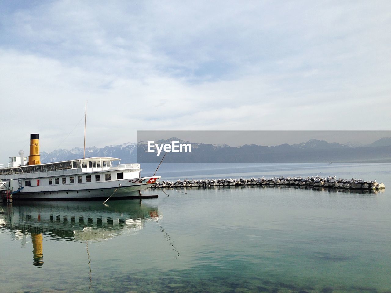 SAILBOATS MOORED ON SEA BY MOUNTAIN AGAINST SKY