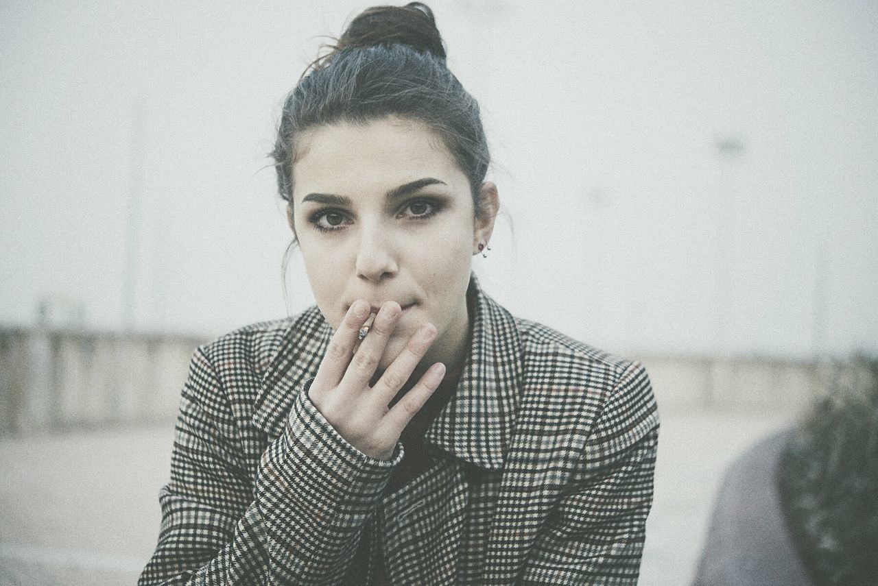 CLOSE-UP PORTRAIT OF YOUNG WOMAN SMOKING OUTDOORS