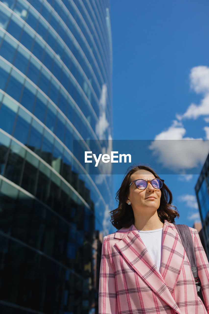 portrait of young woman wearing sunglasses standing against sky