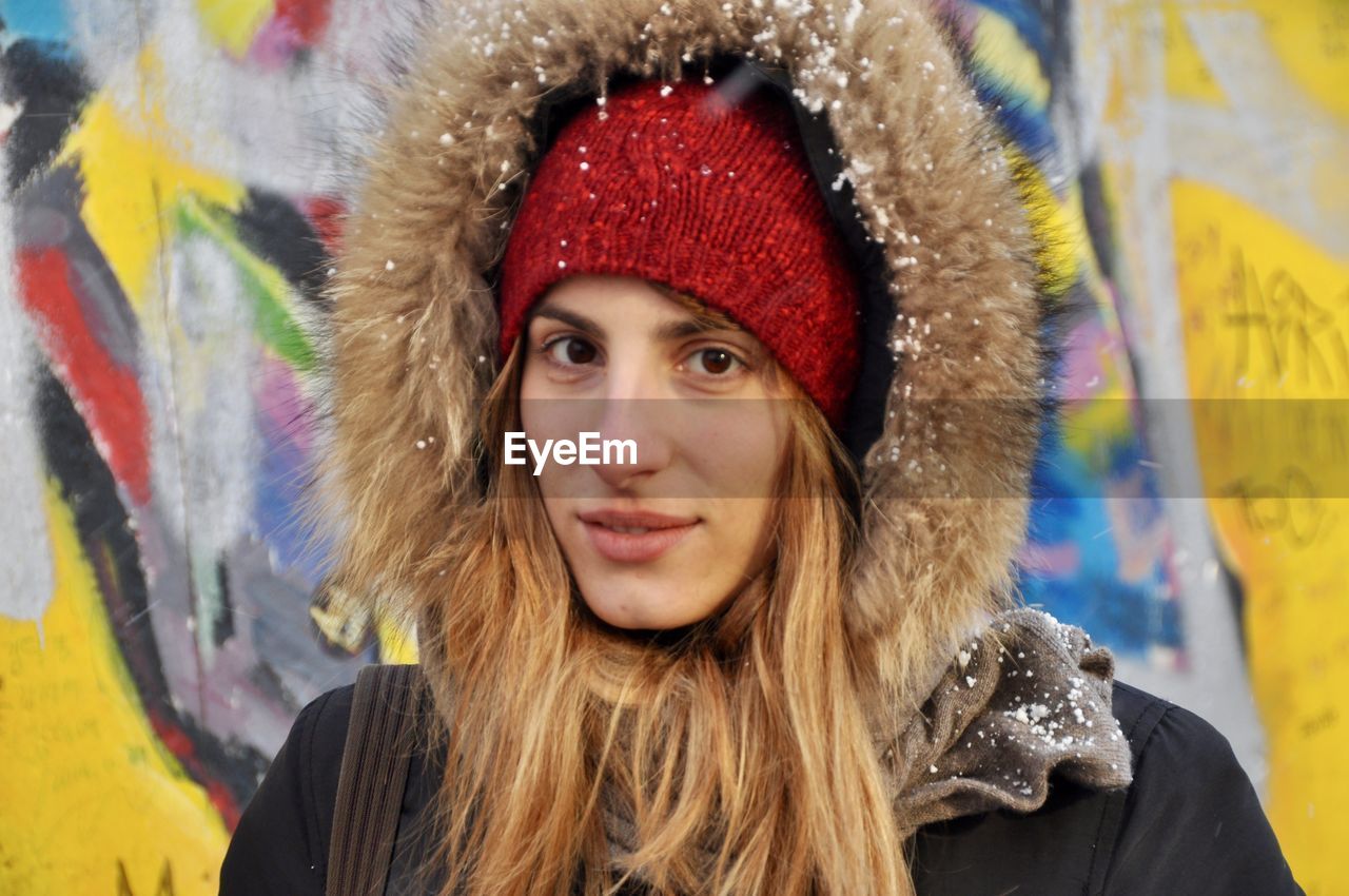 Portrait of smiling young woman standing in city during winter