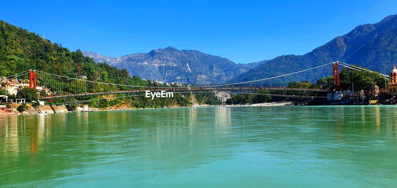 Scenic view of river and mountains against blue sky