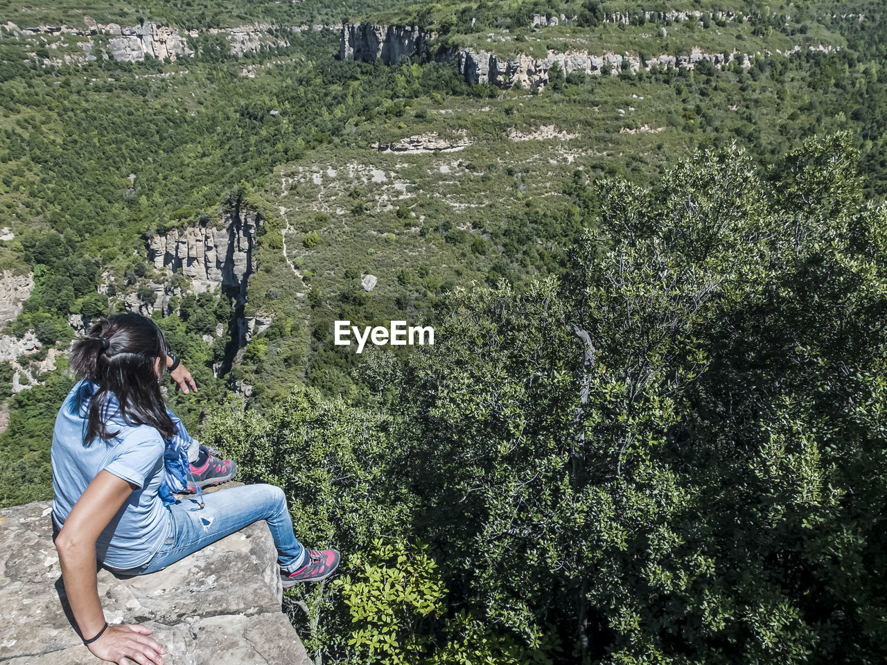 plant, one person, leisure activity, nature, lifestyles, women, casual clothing, full length, day, green, sitting, adult, land, tree, high angle view, young adult, outdoors, growth, beauty in nature, activity, sunlight, adventure, relaxation, flower, tranquility, grass, rock, person, female, side view, non-urban scene, clothing, environment