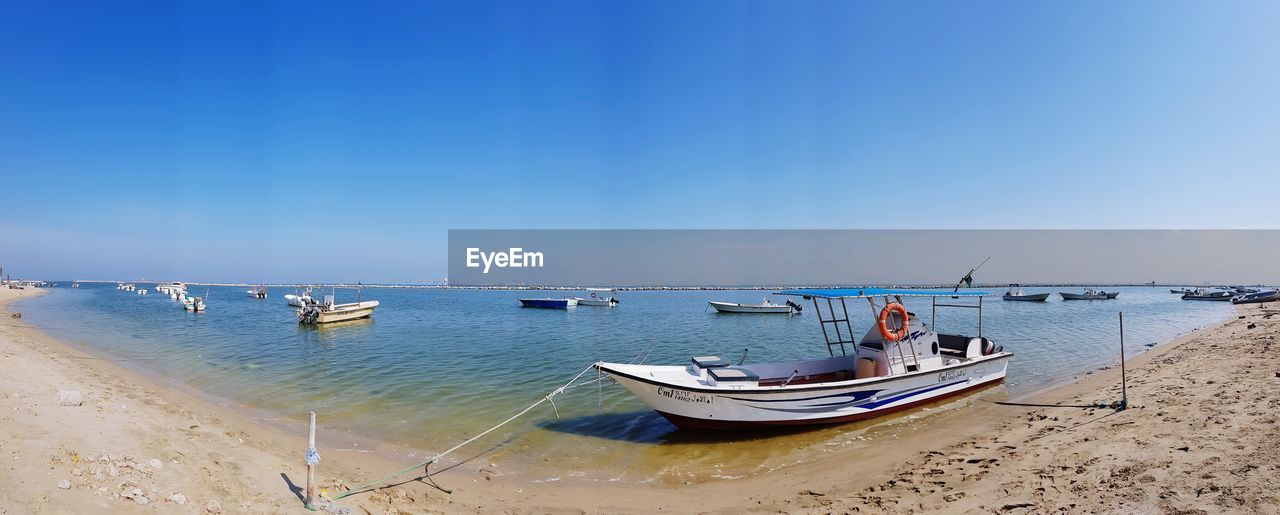 BOATS MOORED ON SHORE AGAINST SKY