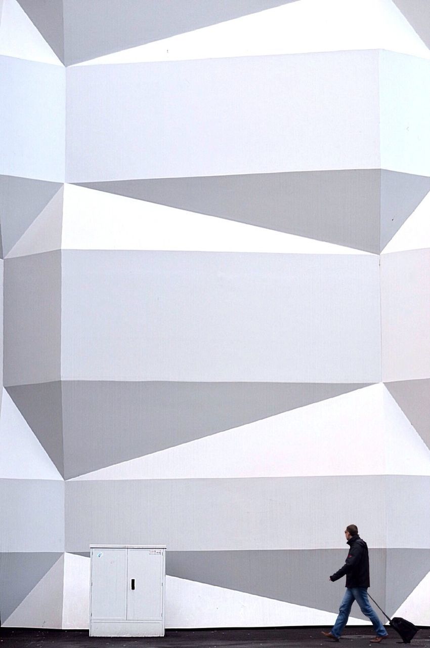 LOW ANGLE VIEW OF WOMAN STANDING IN MODERN BUILDING