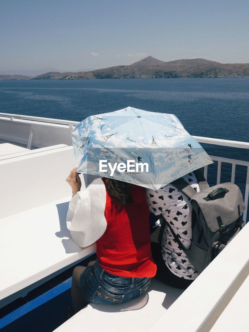 High angle view of couple under umbrella sitting on boat deck against sky