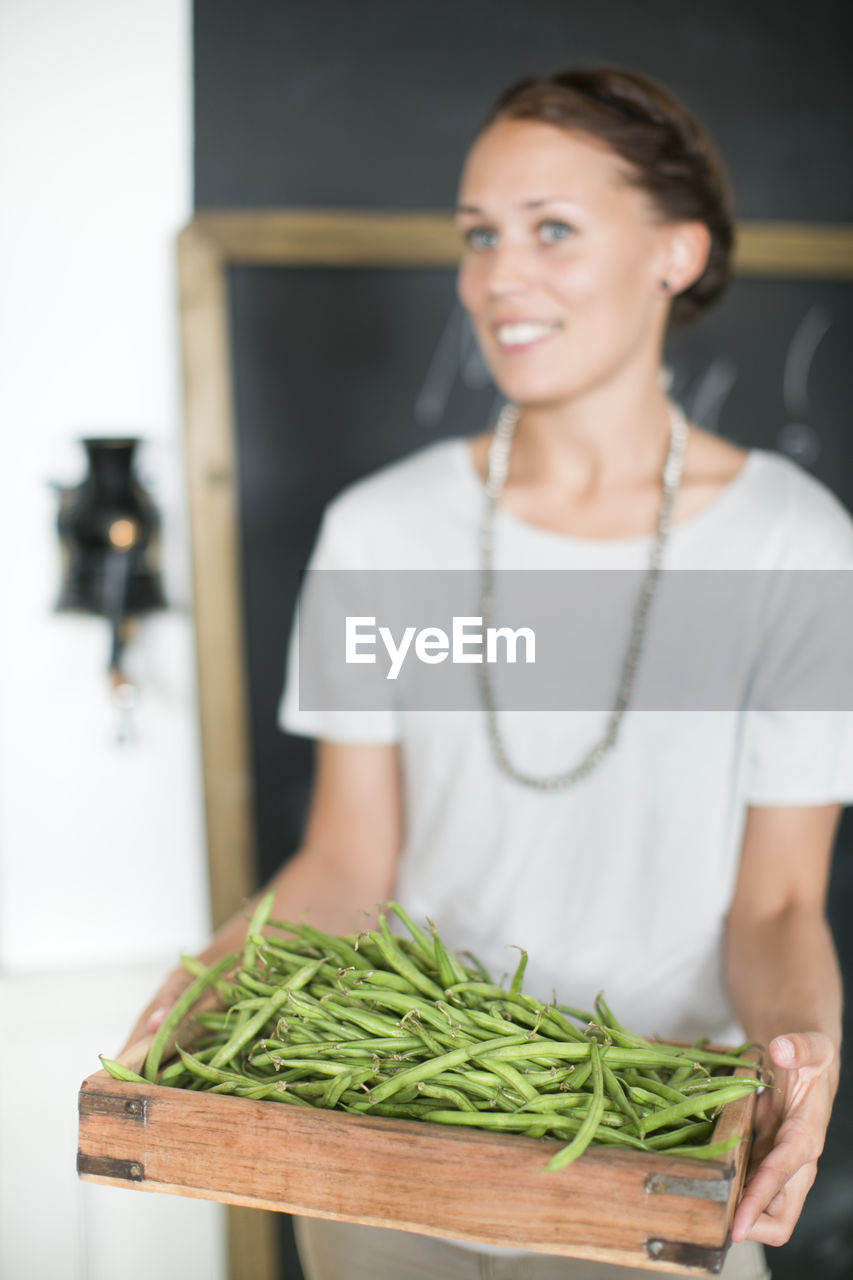 Woman holding green beans in wooden box