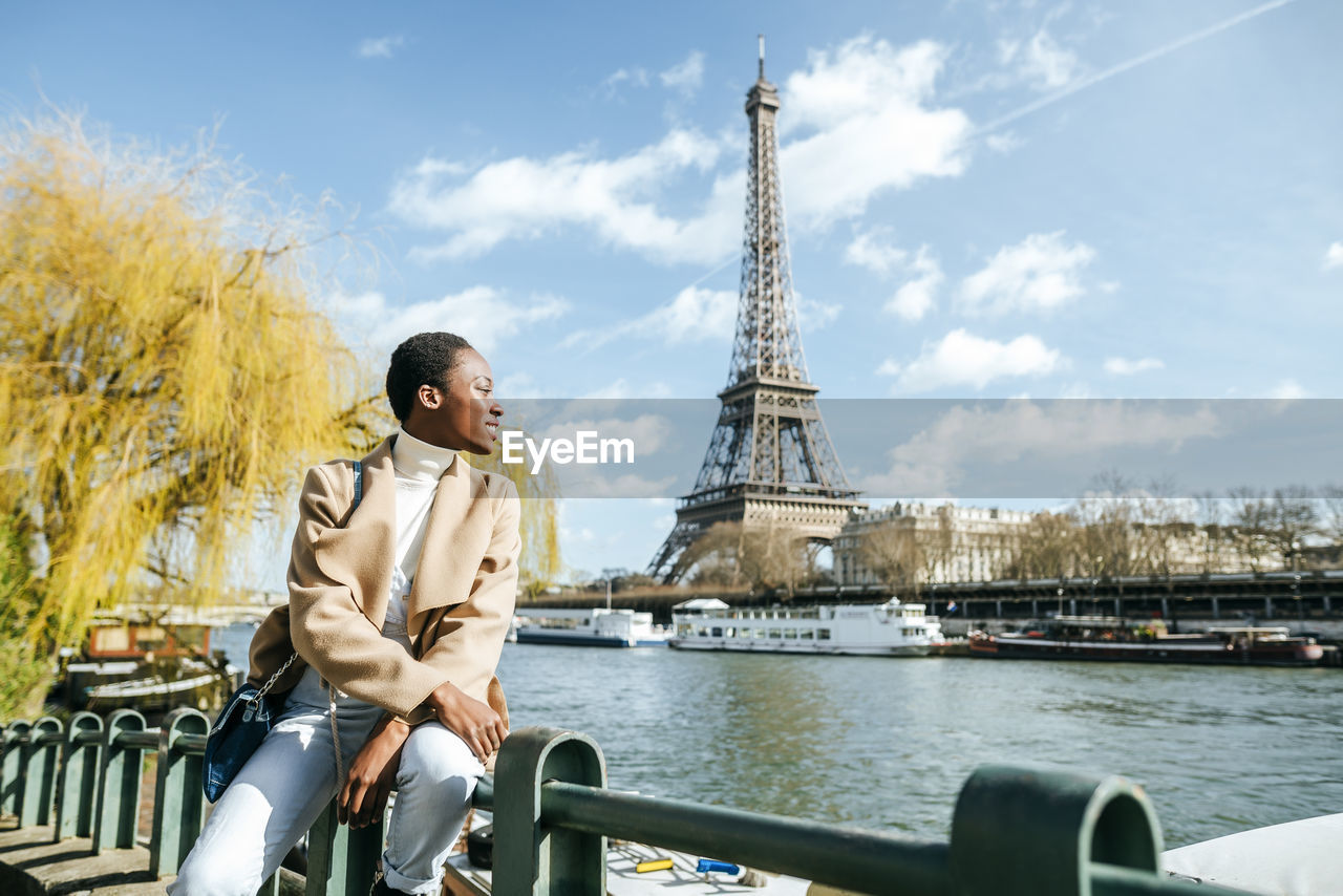 France, paris, smiling woman at river seine with the eiffel tower in the background
