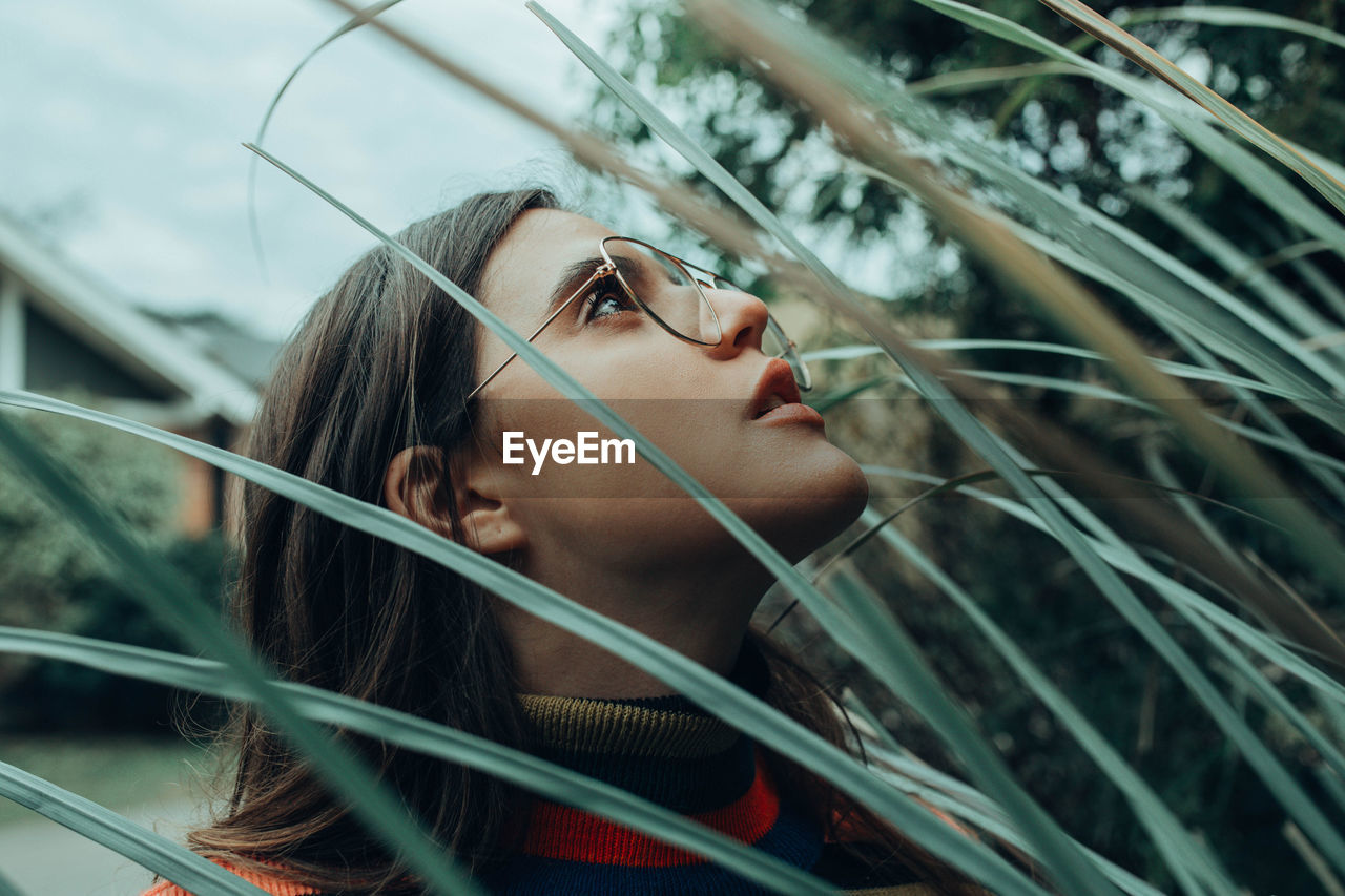 CLOSE-UP PORTRAIT OF YOUNG WOMAN LOOKING DOWN OUTDOORS