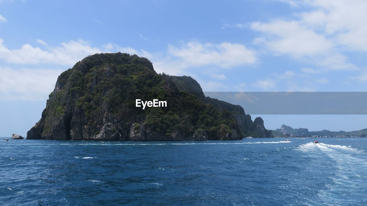 Rock formation in sea against cloudy sky