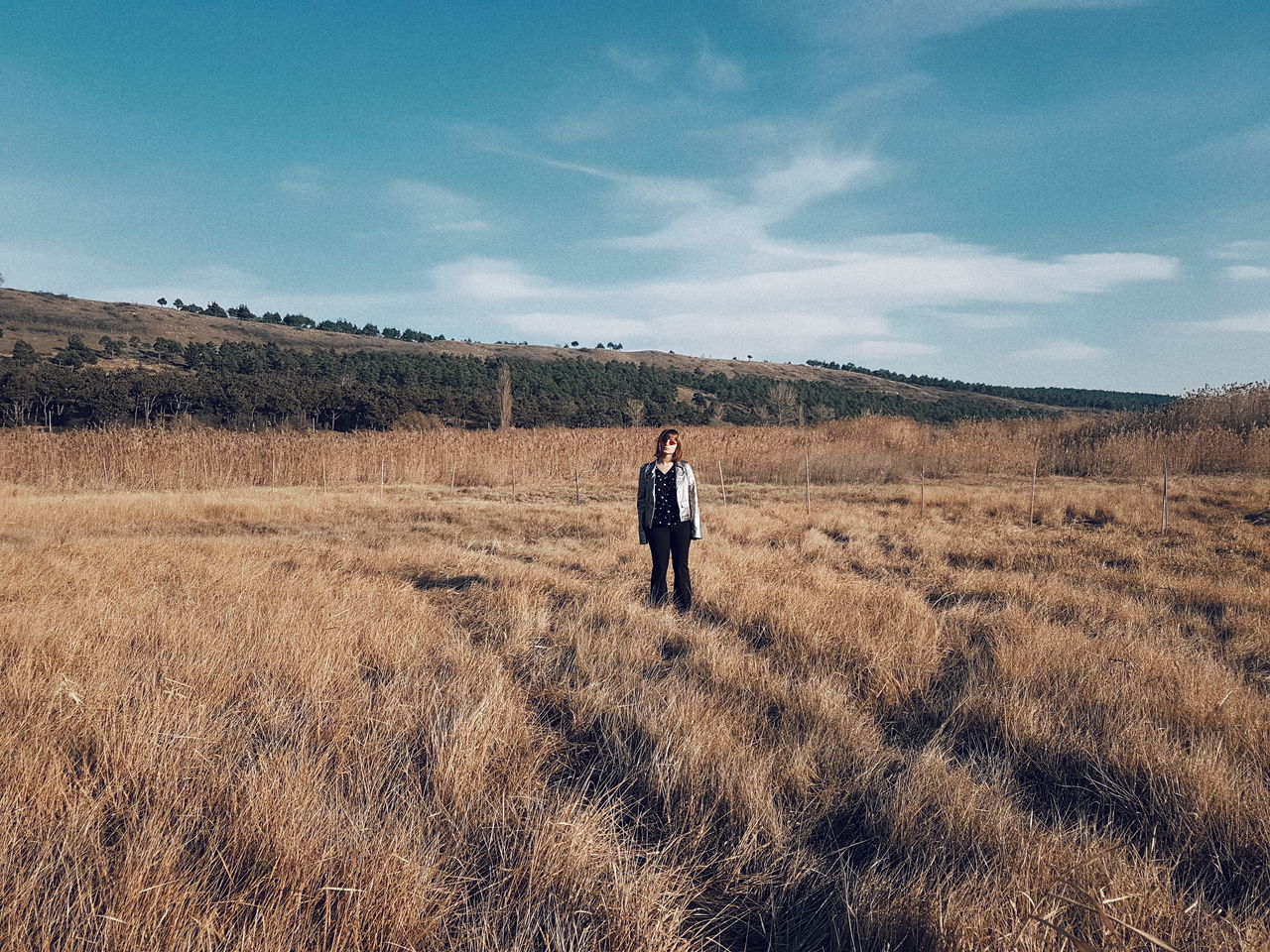 Full length of young woman standing on grassy field against sky during sunny day