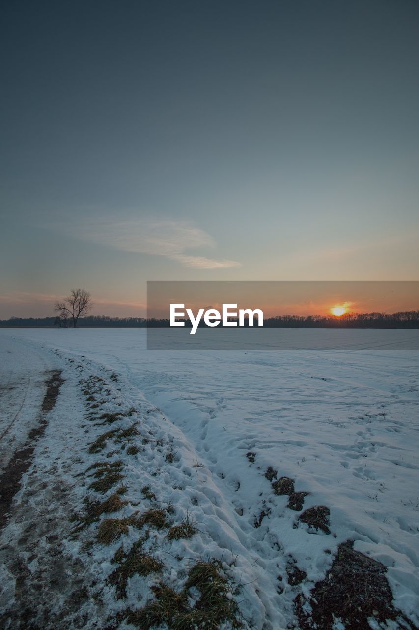 Scenic view of snowcapped landscape against sky at sunset