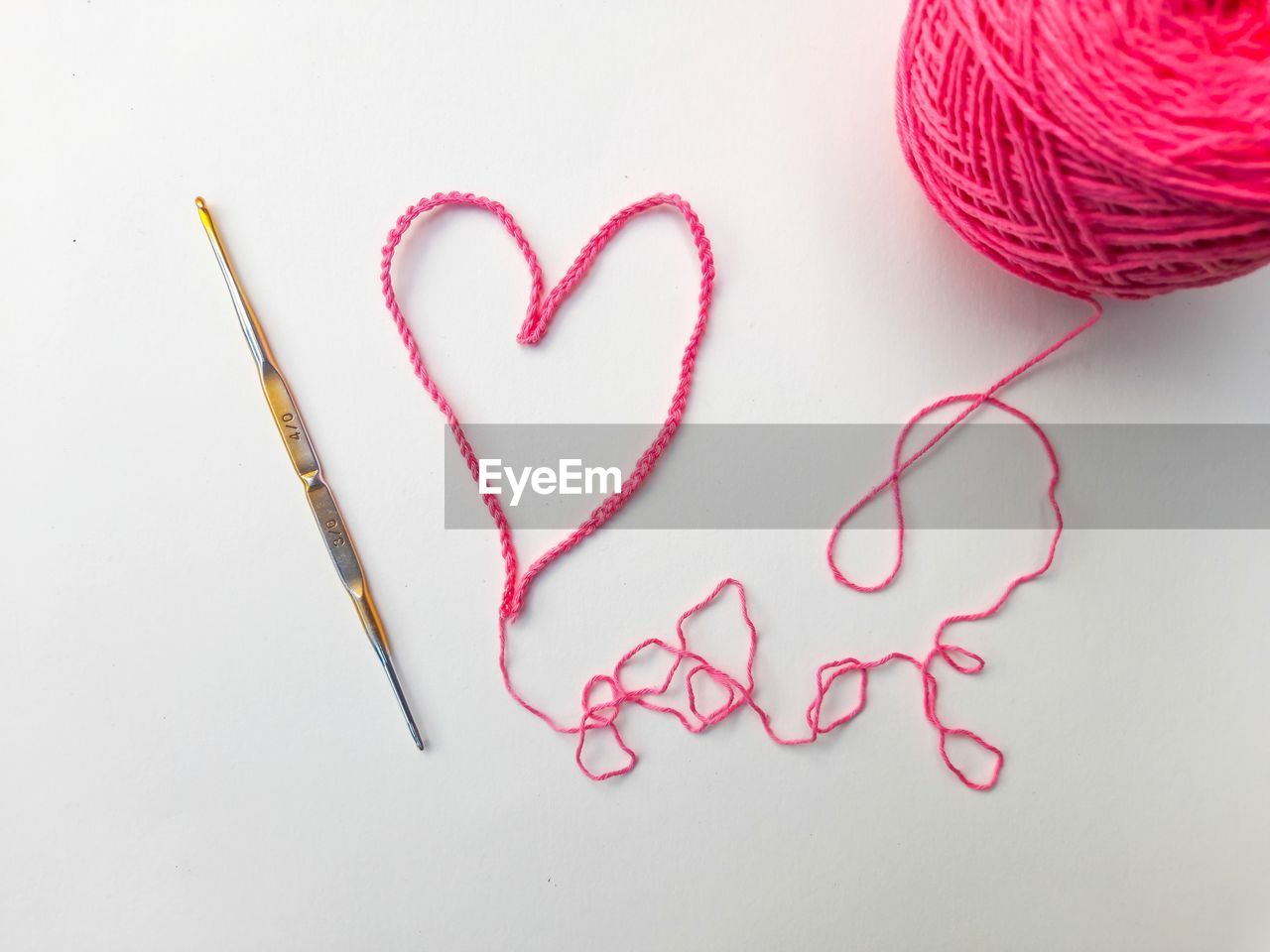 Close up of pink threads forming a love icon on a white background